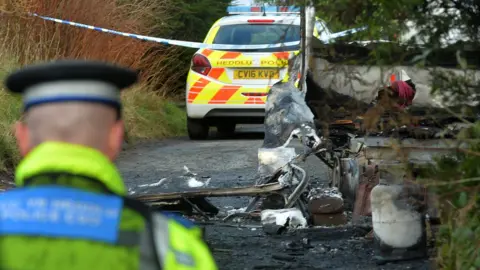 Wales news service A police car and officer at the scene