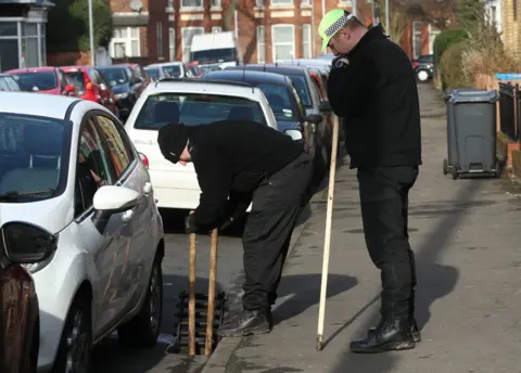 PA Two men looking into a drain on the roadside