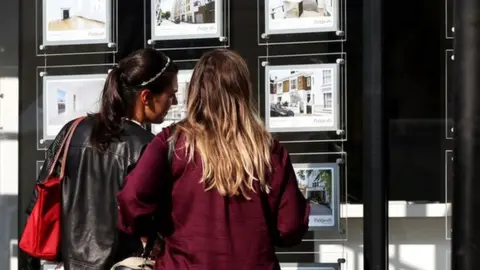 PA Media Two women look at houses in an estate agent's window