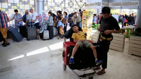 Reuters A child sits on top of luggage on a trolley as tourists queue to leave Lombok Island