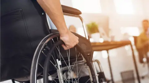 Getty Images A man in a wheelchair working in an office