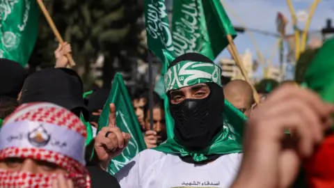 Demonstrators carry Hamas flags at a protest against the war in Gaza, after Friday prayers in Hebron, in the occupied West Bank (8 December 2023)