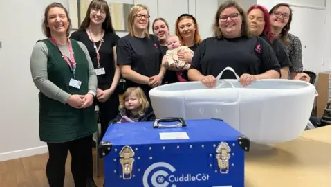 Olivia Cadwallader Olivia Cadwallader handing over the new cuddle cot to staff at St Michael's hospital