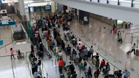 Reuters Travellers queue for shuttle buses to head to quarantine hotels at Hong Kong International Airport