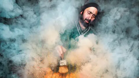 Street food vendor surrounded by smoke as they prepare food