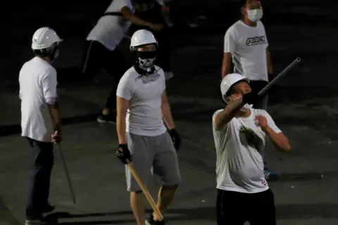 Reuters Men in white T-shirts with poles are seen in Yuen Long after attacked anti-extradition bill demonstrators at a train station, in Hong Kong, China July 22, 2019.