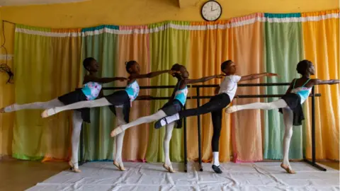 AFP Young dancers dressed in matching leotards hold a ballet barre during a class.