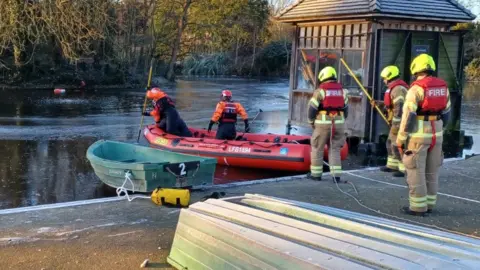 LFB Firefighters head off on the lake while a soggy Ponzo looks on in the distance