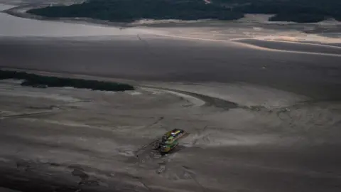 Getty Images Aerial view of raft with vehicles, gas and supplies gets stuck in the dry bed of the Rio Negro on October 3, 2023 in Manaus, Brazil.