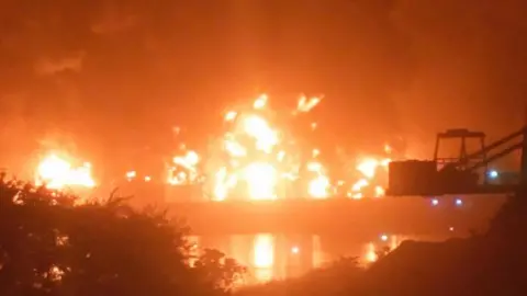 Fire burns after a blast at an oil terminal in Conakry, Guinea, December 18, 2023, in this screengrab obtained from a social media video