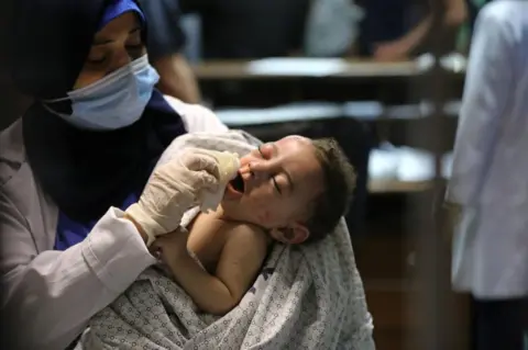 Getty Images A baby injured in Israeli attack carried out to home of Palestinian Abu Khatab Family living in Al-Shati Camp in Gaza Strip, being brought to Shifa Hospital on May 15, 2021, in Gaza City, Gaza