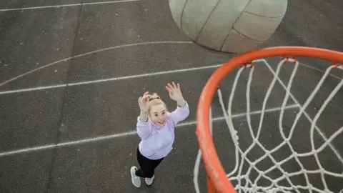 Getty Images Girl scores netball goal