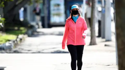 Getty Images A woman walking wearing a mask in Auckland