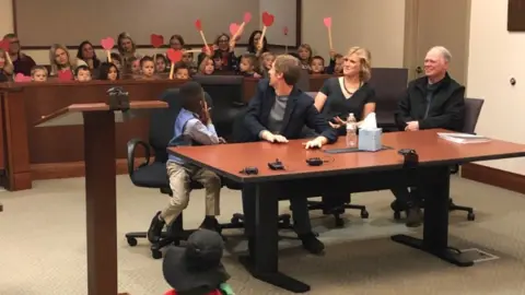 Kent County Court A picture shared by Kent County, Michigan's Facebook page shows a little boy named Michael being formally adopted in court, watched by his Kindergarten classmates