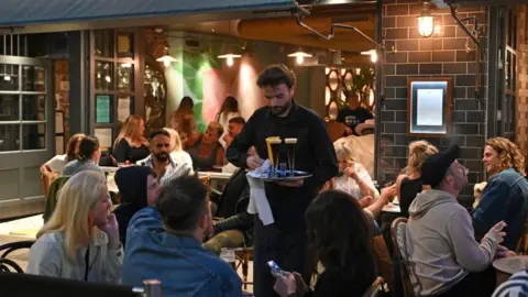 AFP A waiter serves drinks to diners at the Old Compton in the Soho area of London