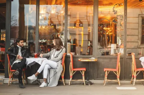 Getty Images A couple sit outside a cafe in Paris