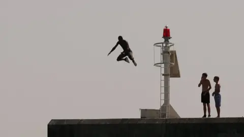 Getty Images Man jumping off rocks into the sea