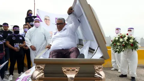 AFP The Mexican candidate for federal deputy of the Social Encounter Party, Carlos Mayorga, launches his campaign inside a coffin, to highlight the country's many thousands of deaths from the coronavirus pandemic and cartel-related violence, at the Zaragoza-Ysleta international bridge in Ciudad de Juarez, Mexico, on 6 April 2021