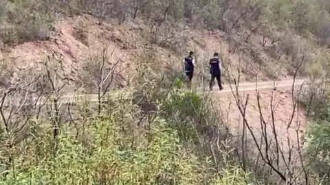 Two police walk along dirt footpath