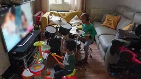 Front room with two children playing on drum sets in front of the TV