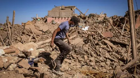 Getty Images A man walks through the rubble of a ruined village