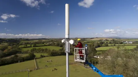 Getty Images An engineer working on a mobile phone mast in a rural setting