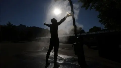 Reuters A man cools off under a water sprinkler during a hot summer day in Vienna, Austria July 30, 2020.