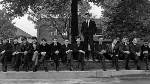 Getty Images Brian Epstein standing with The Beatles, Gerry and the Pacemakers, and Billy J Kramer and The Dakotas sitting down