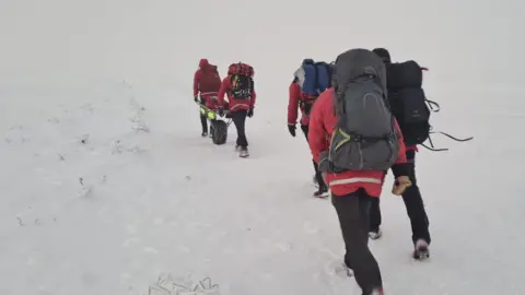 Glossop Mountain Rescue Rescuers walk through snow