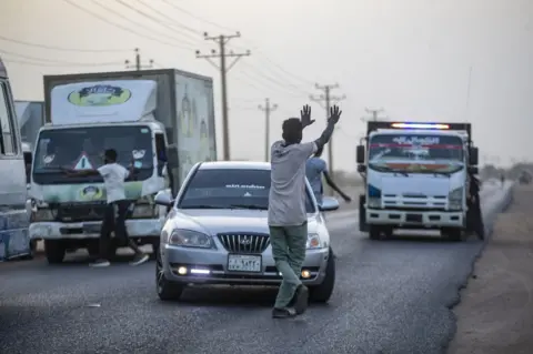 Getty Images A Sudanese man goes infront of cars to invite passengers to join an iftar dinner in Khartoum, Sudan - Saturday 25 March 2023