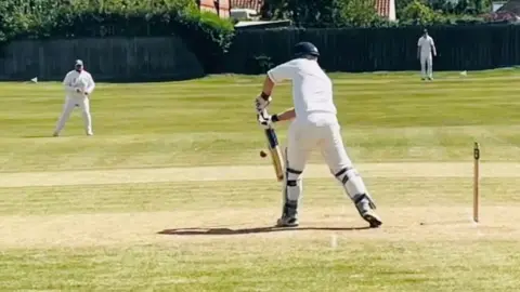 People play cricket on a field