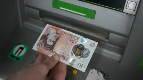 Getty Images Cash being withdrawn from ATM
