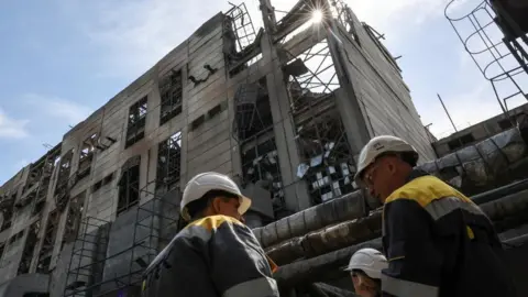 Reuters Workers at the site of a damaged power plant, the building has been hit by some kind of air strike