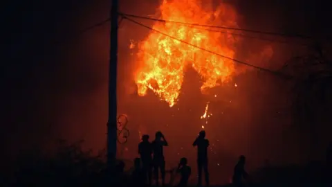 AFP Protesters watch an official building in flames in Basra, Iraq, 6 September 2018