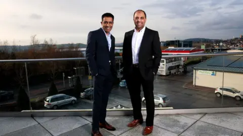 Alamy Mohsin and Zuber Issa pose on a balcony in Blackburn