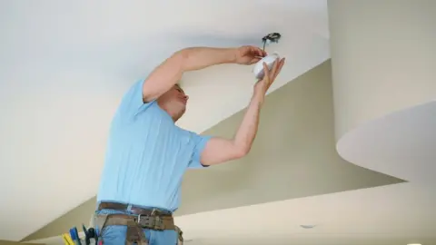 Getty Images Electrician fitting a smoke alarm