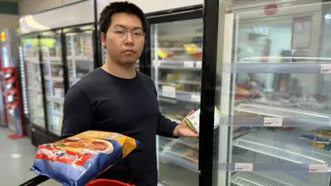 BBC Cheng Gong standing next to freezer