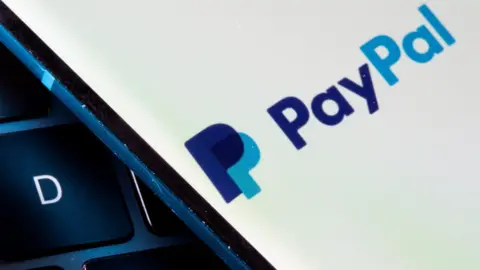 Reuters PayPal logo on a phone sitting against a keyboard in close-up