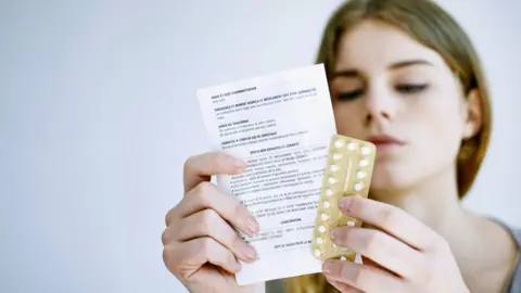 Getty Images young woman reading instructions on pill packet