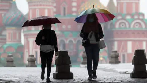 Getty Images People walk under umbrellas in Red Square on 29 May 2020