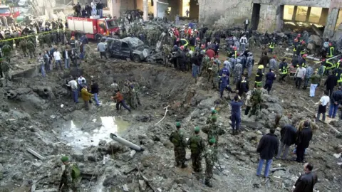 Getty Images Security personnel surround the crater left by the explosion that blew up the motorcade of former Lebanese Prime Minister Rafik Hariri, 14 February 2005
