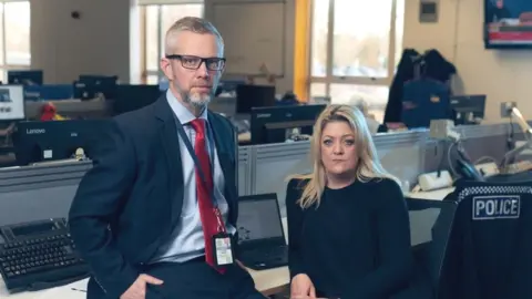 Picture of two people sat at desks in police office