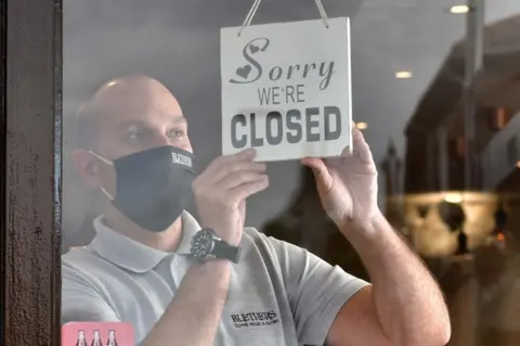 Pacemaker A man puts a "closed" sign in the window of his cafe in 2020