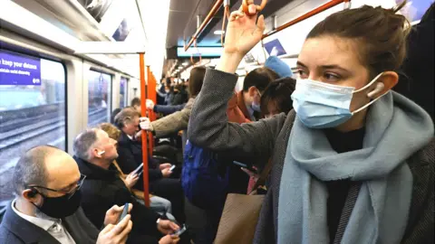 AFP Commuters, some wearing face coverings, travel on a packed London Overground train service on 1 March 2022