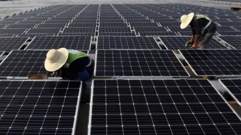 Getty Images Workers at the world's largest floating solar power plant in a lake in Huainan