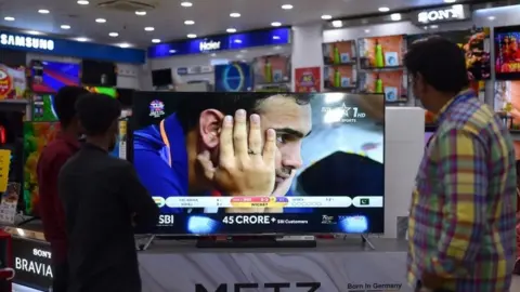 EPA Indian cricket fans watch the first match between India and Pakistan International Cricket T20 World Cup Super 12 stage in Dubai, live on a television