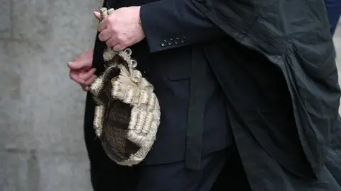 Getty Images A barrister holds his wig as he arrives at The Old Bailey