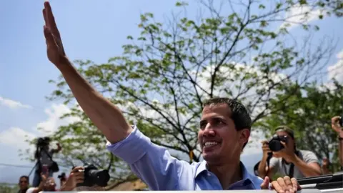 AFP Venezuelan opposition leader and self-declared president Juan Guaido waves to supporters during a rally in Guatire, Miranda state, Venezuela on May 18, 2019.