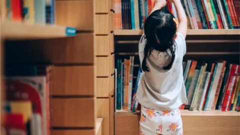 d3sign via Getty Toddler looking at bookcase