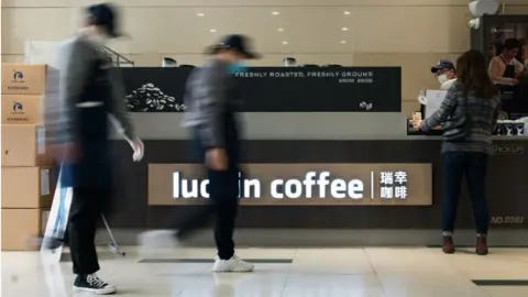 Getty Images Server wearing a protective masks at a Luckin Coffee shop in Shanghai, China.